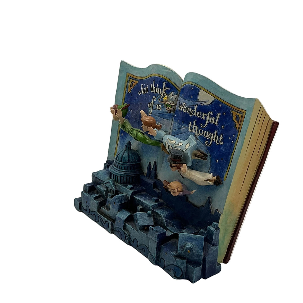 A decorative book-shaped sculpture or bookend featuring an open illustrated book with fantasy characters and the phrase 'Just think of this wonderful thought,' set on a blue castle-like base against a plain light gray studio background.