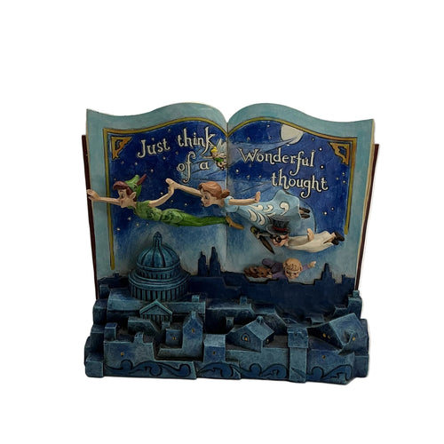 A decorative book-shaped figurine or bookend featuring Peter Pan and Tinker Bell flying above a blue cityscape, with the text 'Just think of us' and 'Wonderful thought' on the open pages, photographed against a plain light gray studio background.